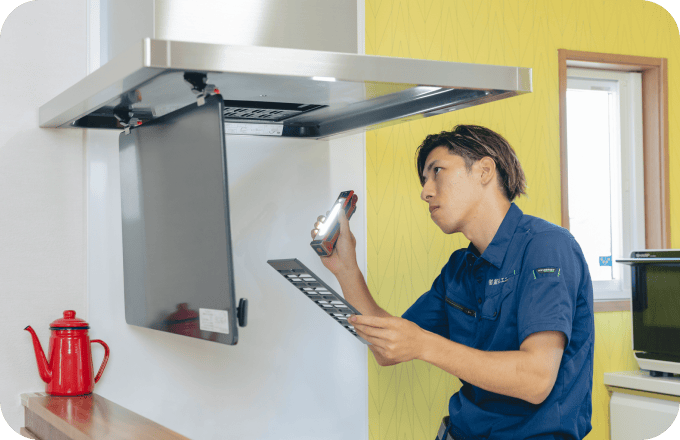 キッチンの換気扇を点検するスタッフ